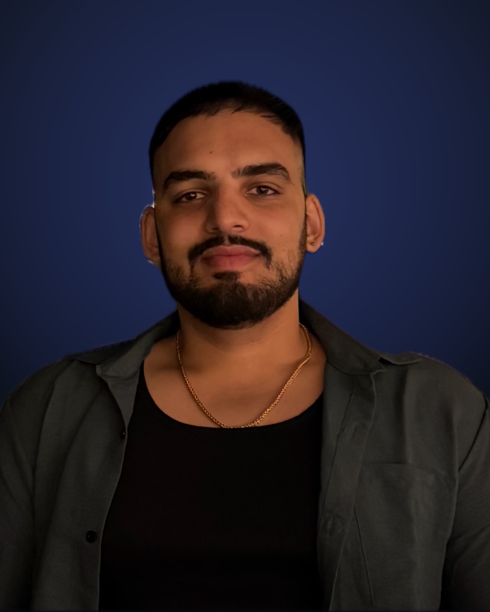 Portrait of Summit Grover in a dark open shirt and gold chain
